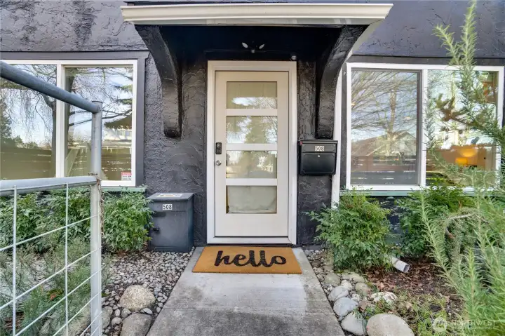A glass front door, modern windows, and vibrant landscaping create a welcoming first impression.