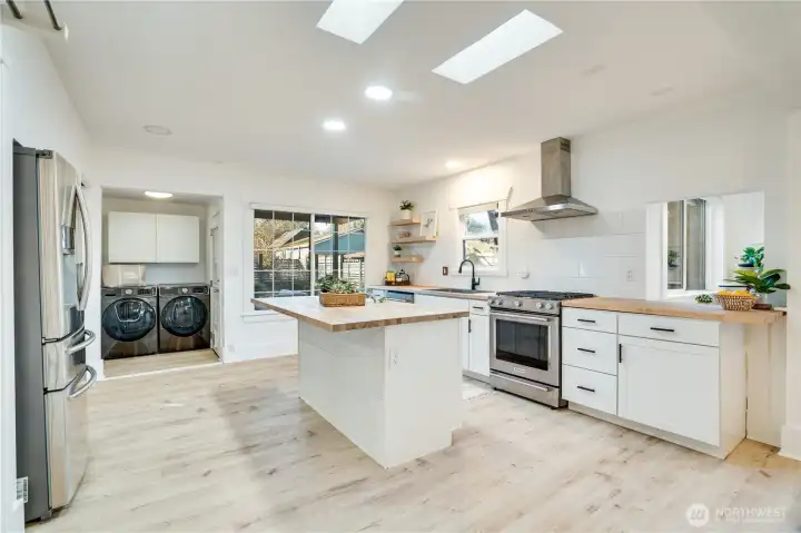 The updated kitchen features butcher block counters, stainless steel appliances, a breakfast bar island, and skylights that keep the space light and bright. Be sure to note the nearby laundry area with extra storage.