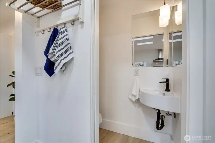 A compact half bath fits seamlessly into the home, featuring a pocket door and corner sink.
