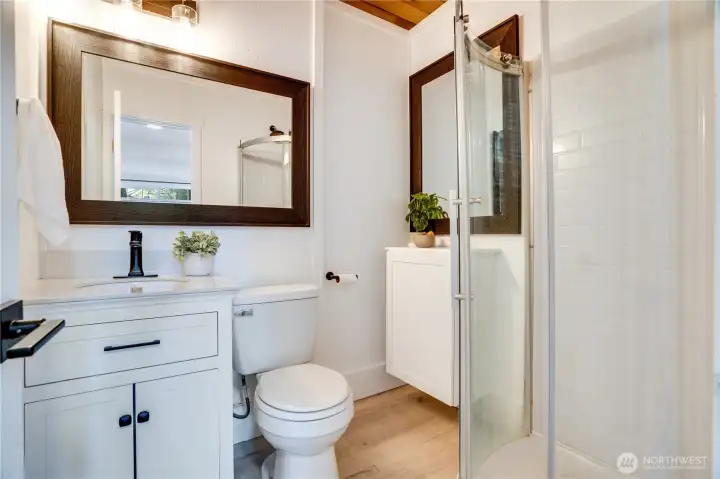 The bathroom features durable vinyl plank flooring, modern lighting, and extra cabinetry for added storage.
