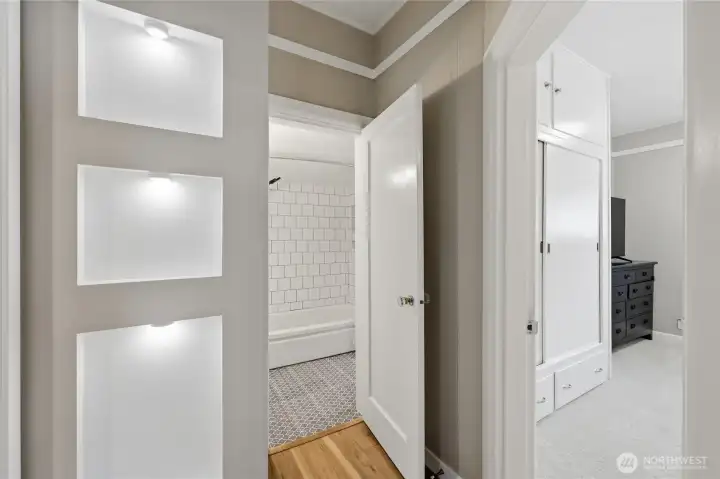 Hallway showing inset shelves leading into the bathroom and a bedroom.