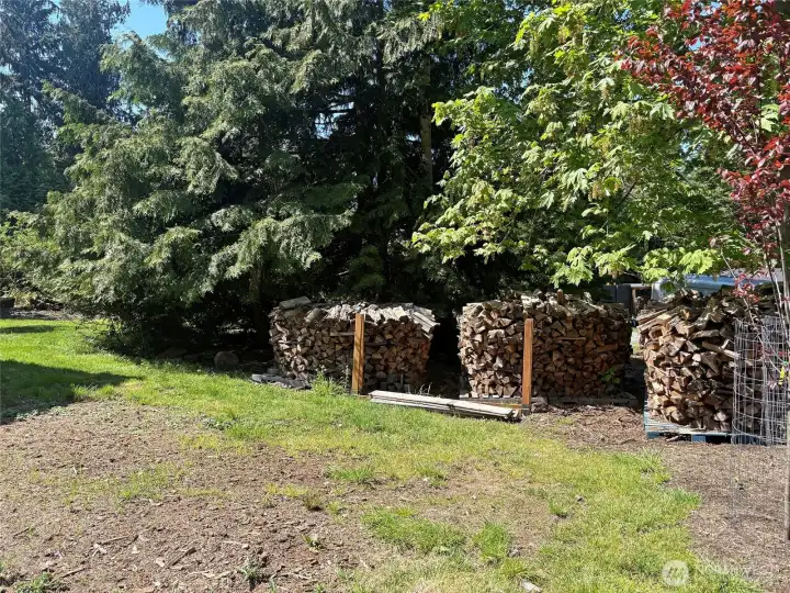 The stacked firewood remains for the wood stove, or the backyard fire pit area.