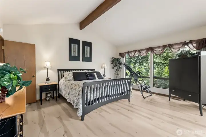 Wall of windows opens large primary bedroom to the outdoors and your private deck.