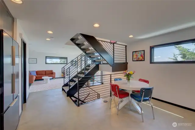 The sculptural staircase unifies the home. The ample kitchen includes space for dining.