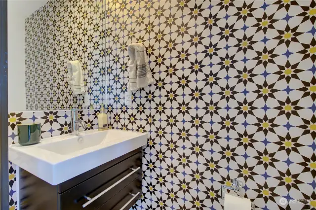 The main level powder room pops with the geometric wallpaper.