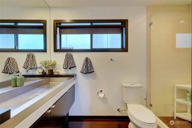 The primary bath design is accented by a stainless steal trough sink with wall mounted fixtures and a walk-in shower.