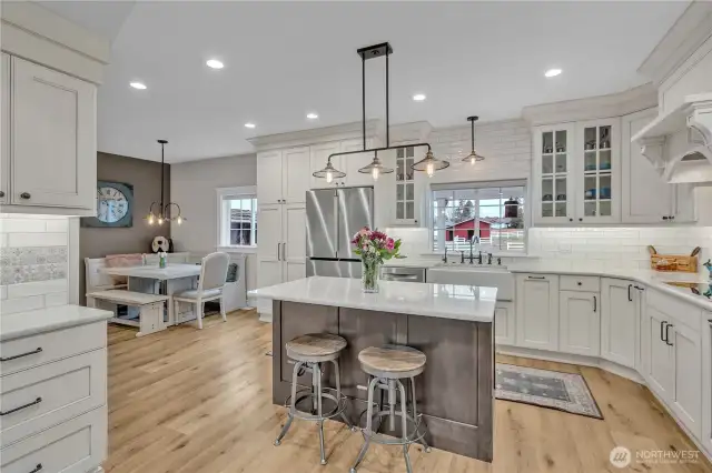 Kitchen with Shaw fir glazed farmhouse sink, Kingston Brass fixtures, Bosch appliances, induction stove top, convection microwave oven, quarts counter tops, Belmont custom glazed cabinets, Duchateau LVP floors and Hinkley light fixtures.