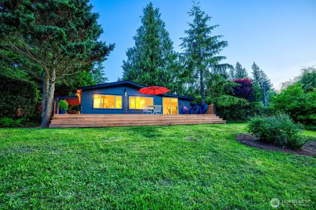 Bathed in twilight and wrapped in cedar, River House Retreat glows with rustic welcome. Set on a parklike half-acre framed by evergreens and birdsong, this 3BD/2BA getaway sleeps 8 and features a 600+ SF deck perfect for morning coffee, stargazing, and stories by starlight.