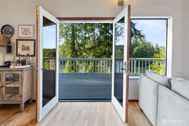 French doors open onto a wraparound porch, showcasing breathtaking views of Whiteman Cove, Puget Sound, and the Olympic Mountains.