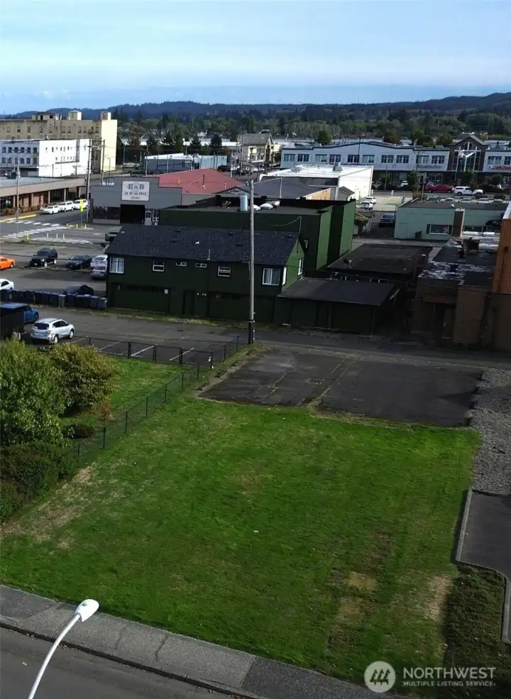 Green frontage along W. 1st Street with 8 paved parking spaces in back, off alley entrance.