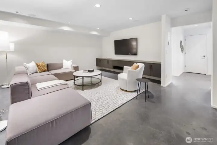 Exceptional rec room/media room, featuring radiant-heated polished concrete floors, built-in cabinets and shelving, and 5.1 surround sound