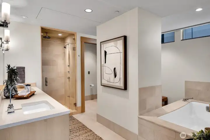 Spa themed primary bathroom with heated tile floors, soaking tub and steam shower.