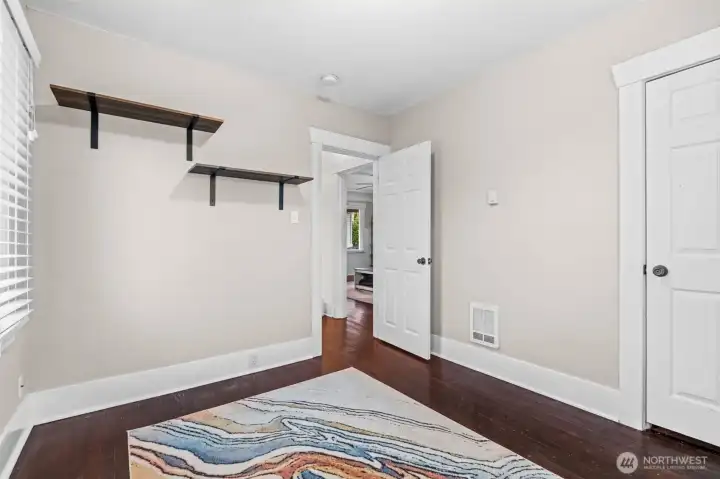 Versatile Bedroom with Custom Shelving and Hardwood Floors