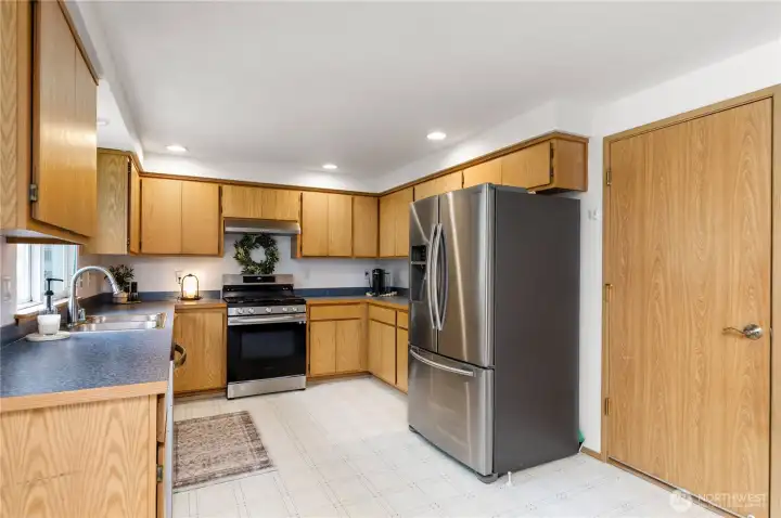 Bright, welcoming kitchen designed for everyday life and special mornings. Gleaming stainless appliances pair with warm cabinetry and abundant storage—deep drawers, pull-out shelves, and a handy lazy Susan keeping pots, pans, and pantry staples neatly within reach. Expansive counters create effortless workspace for meal prep, communal baking, or casual coffee and conversation. The centerpiece gas stove, complete with a built-in grill, promises smoky, golden breakfasts and weekend brunches that linger over the table. Soft under-cabinet lighting and a sunlit window make the room feel airy and inviting—equal parts practical and comforting, ready for family dinners and spontaneous gatherings.