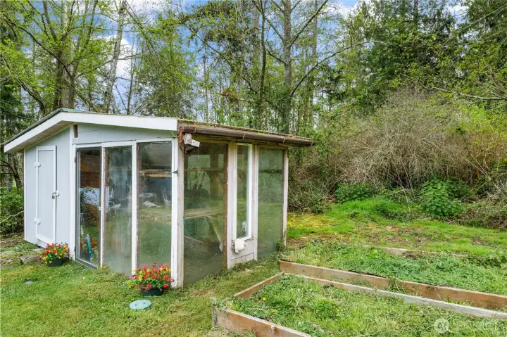 This home even has a cute Greenhouse with a table and shelves so you  can garden. Two large garden beds. Storage on one side.