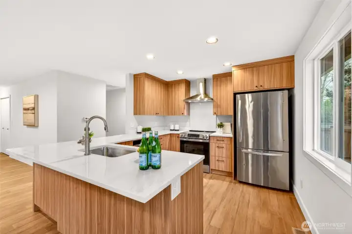 The 2026 kitchen remodel delivers a true chef's workspace, with a professional-grade stainless range, wall-mounted chimney hood, and custom walnut-tone cabinetry extending from counter height all the way to the ceiling for exceptional storage. The generous quartz peninsula with undermount sink and hardwood floors completes a kitchen that feels both high-end and highly functional.