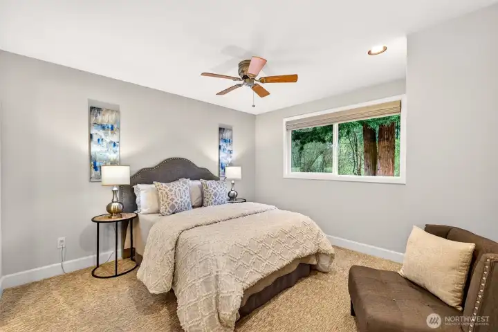 The primary suite offers a quiet, well-appointed retreat with updated carpet, a ceiling fan and a window looking directly into the wooded greenbelt.