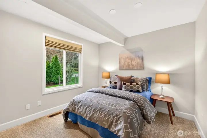 This bedroom offers a cozy and private feel with a garden view window, plush carpet, and a compact footprint perfectly suited for a guest room, home office, or secondary sleeping space.