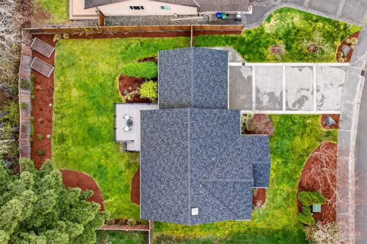 The 2021 roof stands out in crisp condition from above, underscoring the level of investment and care that has gone into this home's long-term maintenance. The aerial view also reveals the full scope of the 8,062 SF lot — generous front and rear yard space, wide driveway, and the composite deck positioned perfectly at the rear of the home against the greenbelt.