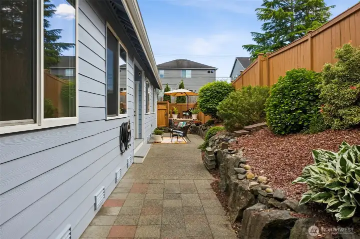 Easy maintenance backyard with decorative rock wall & patio pavers for easy access to gates on both sides of home + natural gas hook up.