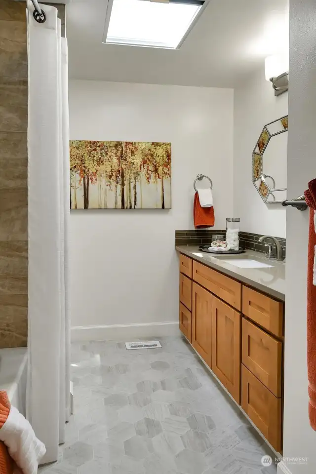 This well-dressed full bath shines with custom tile and handsome fixtures.