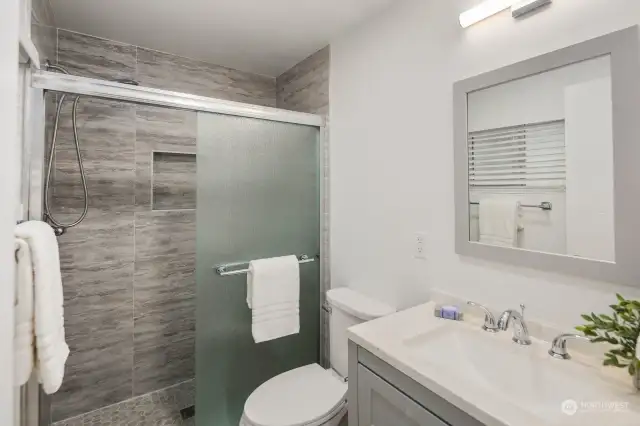 In the updated bathroom of the primary bedroom, modern sophistication meets timeless charm. A large tiled walk-in shower stands as the centerpiece, offering both luxury and convenience. The matching coloring and updates throughout the house are seamlessly reflected here, creating a cohesive and elegant aesthetic that elevates every moment of self-care.