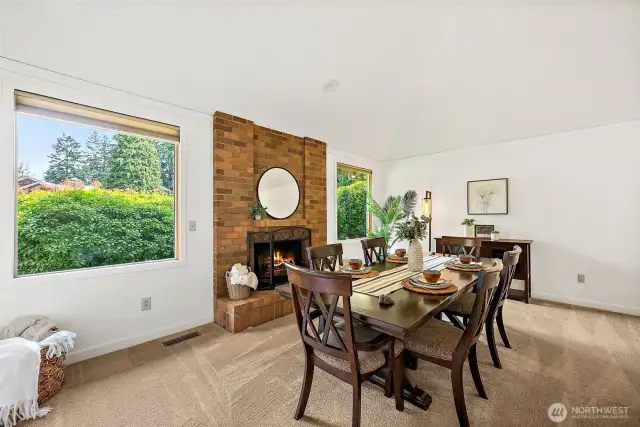 The front living room, being used as a formal dining space, features large windows vaulted ceilings and one of two wood burning fireplaces.