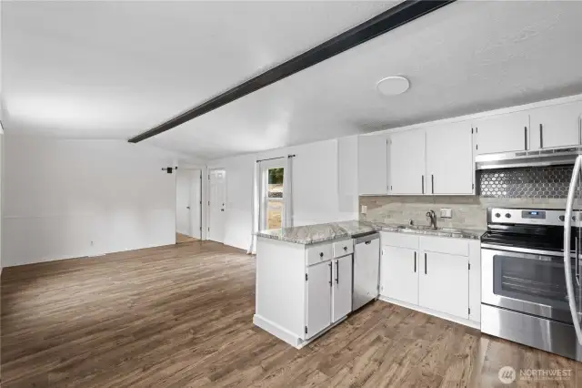 Open floor plan with laminate floors, granite countertops, and stainless steel appliances