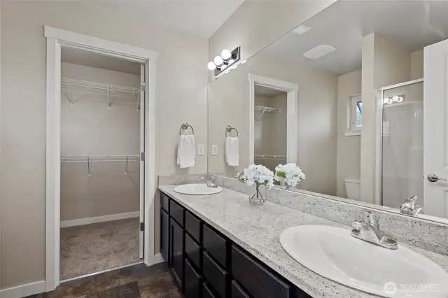 Primary bathroom showing double sinks and the door in back leads to a large wardrobe closet.