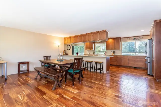 This angle captures the scale of the dining and kitchen combo, showing off the generous space for entertaining. The dining area is well-positioned near the kitchen island, while expansive counters and cabinetry provide ample prep and storage. With windows on both sides, the room feels bright and open. The cohesive flow between dining and kitchen makes this a versatile gathering space designed for convenience and comfort.