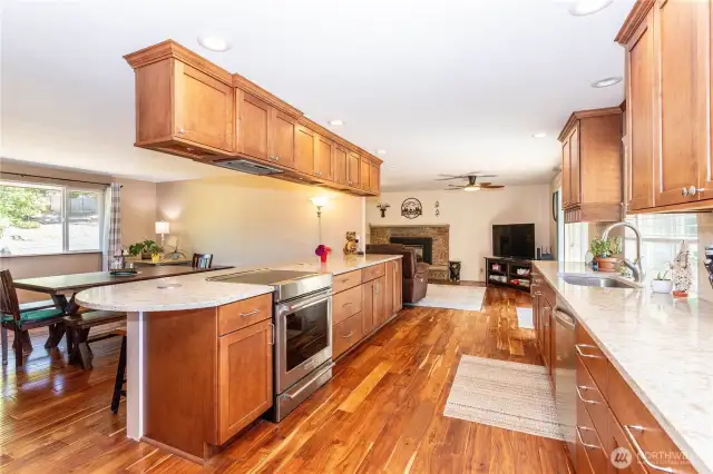 From this view, you see the natural flow between kitchen and living areas. The expansive island doubles as a prep and serving space, while overhead cabinets provide extra storage. The open design ensures the chef is never left out of the action, with clear sightlines into the dining room and cozy living area with a fireplace. This setup combines practicality with a true sense of home, making it ideal for gatherings of all sizes.