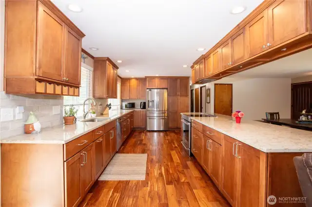 This angle captures the full symmetry of the kitchen. Dual rows of cabinets and counters create a balanced, functional workspace. The overhead cabinetry adds storage without compromising openness, while recessed lighting ensures a bright, welcoming environment day or night. The kitchen’s design blends modern updates with timeless craftsmanship, making it both efficient and stylish—a true centerpiece of the home.