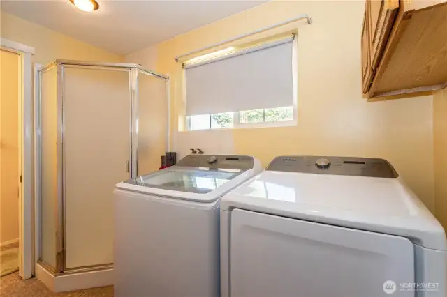 The laundry room is more than just practical—it features a full-size washer and dryer along with a separate shower, offering extra flexibility for busy households. A window brightens the space, while built-in cabinetry provides storage for supplies. This dual-purpose setup is ideal for keeping daily chores streamlined, and the additional shower makes it perfect for guests, pets, or a quick rinse after outdoor activities.