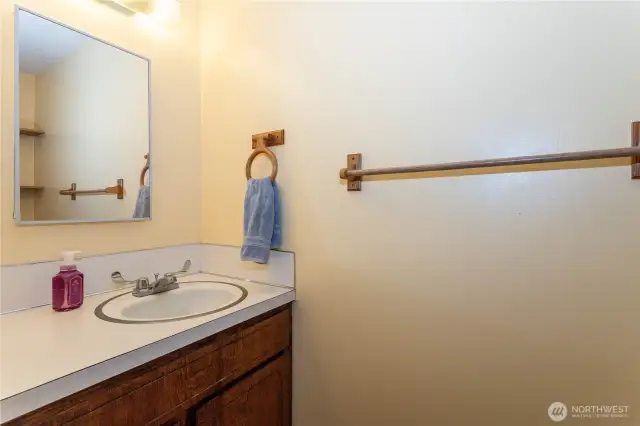 This convenient half bath is tucked into the home for easy access. With a simple vanity, mirror, and warm wood cabinetry, it offers practicality in a compact space. Neutral finishes make it easy to update or personalize. Perfect for guests or quick use, it adds functionality to the home’s layout and ensures comfort for everyday living.