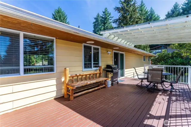 This expansive back deck is built for entertaining, offering plenty of room for outdoor dining, grilling, or just relaxing. A rustic bench and ample space for a barbecue make it easy to imagine hosting summer gatherings. Sliding doors connect the deck directly to the living room, extending your living space into the outdoors.