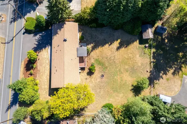 This aerial shot shows the full scope of the property, a spacious lot with endless possibilities. The home sits toward the front, giving you a massive backyard perfect for entertaining, gardening, or future expansions. A covered patio and a firepit area invite outdoor living, while mature trees add both privacy and charm. The wide-open space makes this lot ideal for pets, play, or simply enjoying the Pacific Northwest seasons. From above, you can see how this property balances accessibility with privacy.