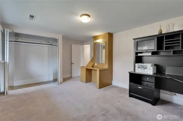 Large mirrored closet and built-in vanity that includes a laundry chute.