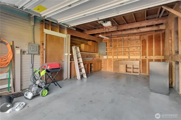 Attached garage with shelving and shop space.