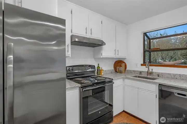 You'll enjoy creating meals in this space with overhead hood vent.  The cook top is conveniently located between the sink and stove.  Subway tile and backsplash with garden window to nourish your favorite herbs.