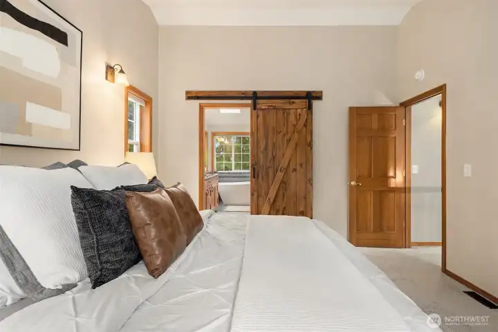 Remodeled primary bedroom with barn door leading to upgraded ensuite