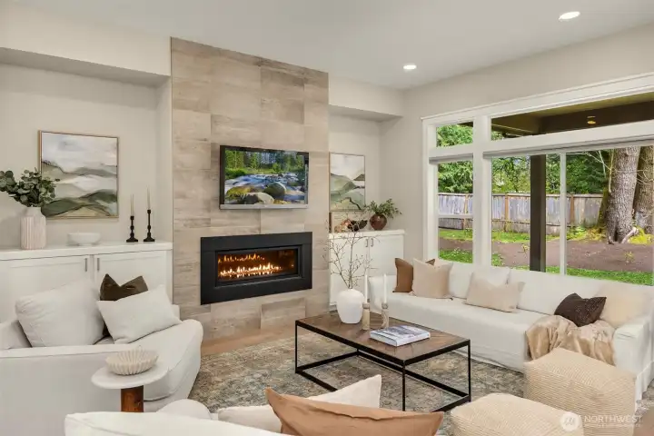 Spacious great room featuring a gas fireplace with tile surround, large picture windows, and an open-concept design perfect for everyday living and entertaining.