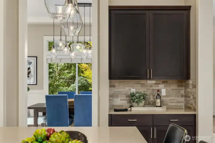 Thoughtfully designed kitchen with additional prep space and built-in storage, opening to a light-filled dining area with modern lighting and garden views.