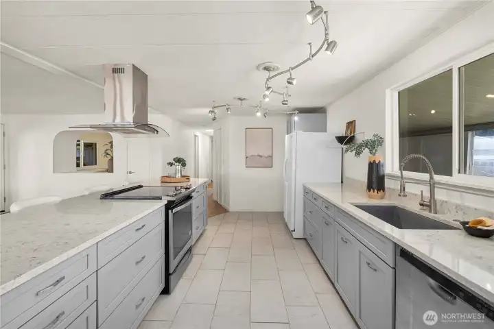 The thoughtfully designed kitchen offers generous prep space with deep drawers for storage, a stainless steel dishwasher and range, plus a deep sink with a commercial-style sprayer—designed for both convenience and style.
