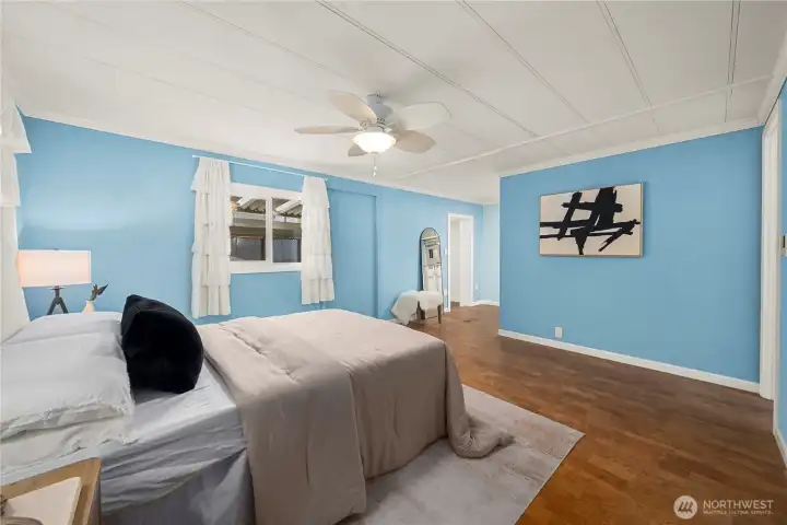 Opposite view of the primary suite highlights its spacious layout, warm cork flooring, and serene ambiance—offering a private retreat with a true coastal feel.