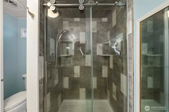 Enjoy a spa-like experience in the tile walk-in shower with modern finishes and a sleek glass sliding door.