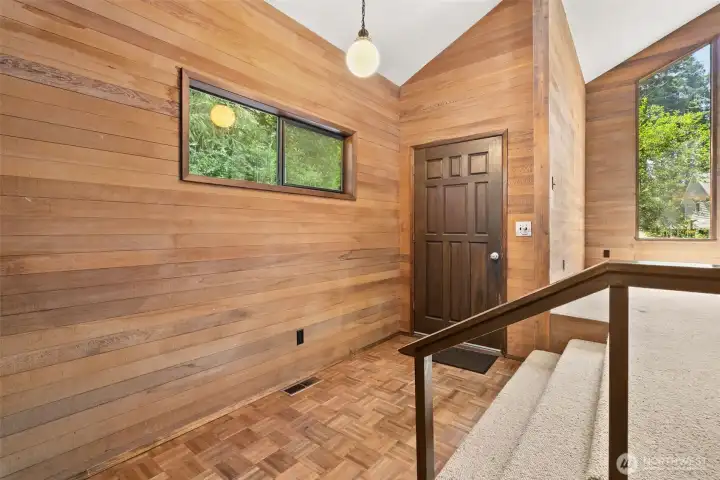 Entry way with parquet flooring and cedar sided walls.