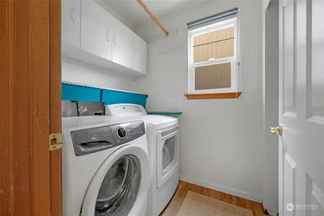 Laundry area with a nice number of cabinets and lots of shelving behind the door.