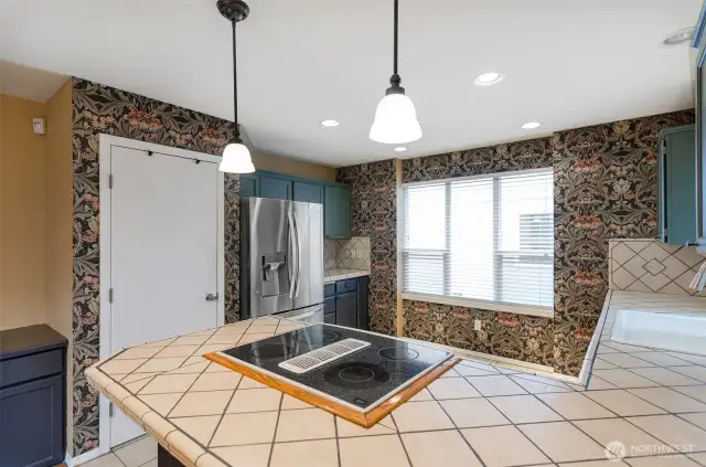 Extended eating area with added built-in cabinetry, pantry and pendant lights over eating area.