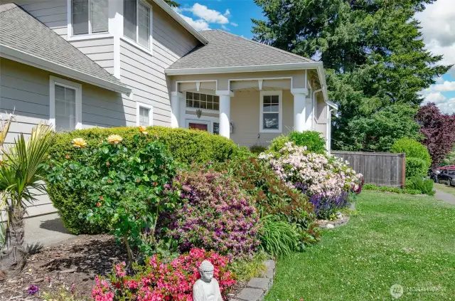 View of the front of the house showing off all these blooming scrubs and architecturally interesting front entry.