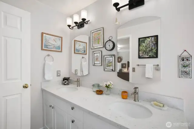 Updated primary bathroom with dual vanities, modern lighting, and stylish finishes.